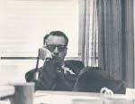 Walter Kramer sits behind his desk in a black and white photo