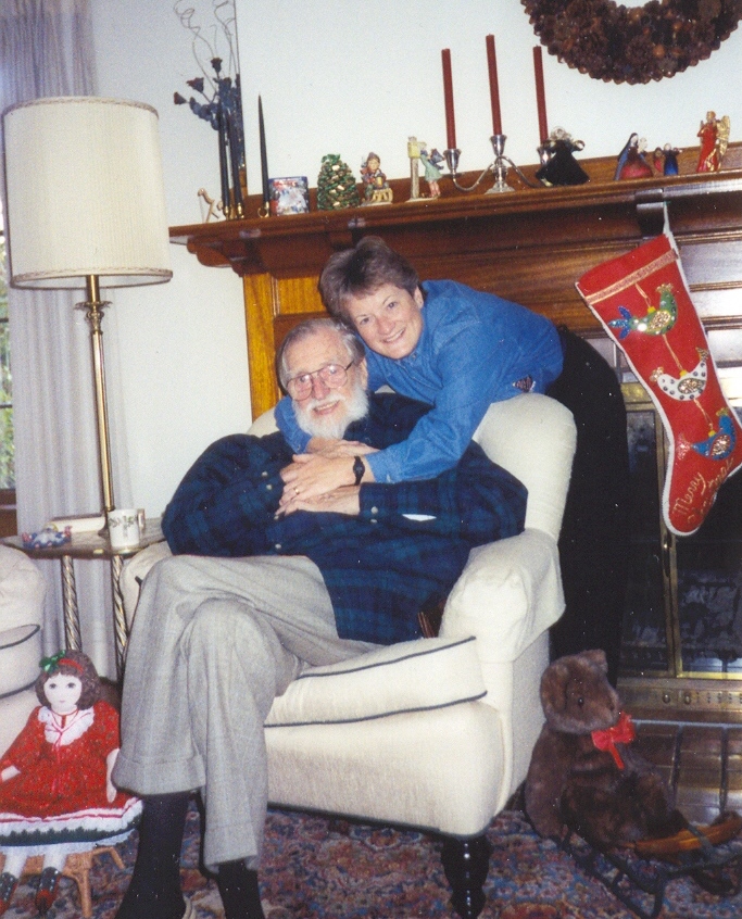 Walter Kramer sits in a chair, hugged from behind by his daughter Mary Jo Chapman. They are surrounded by Christmas decor.