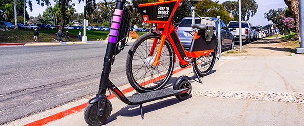 Escooter and bike parked on sidewalk